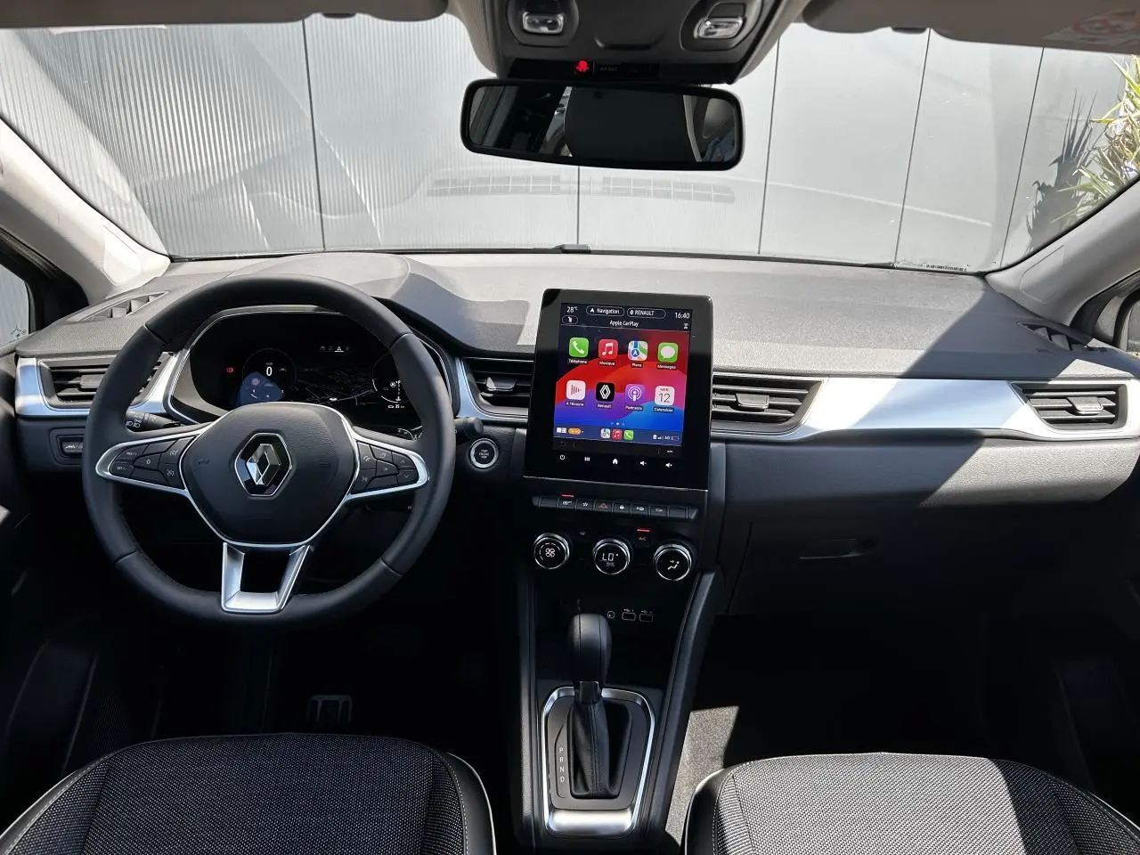 Vue intérieure frontale du tableau de bord du Renault Captur 2024 avec écran tactile vertical et volant multifonction.