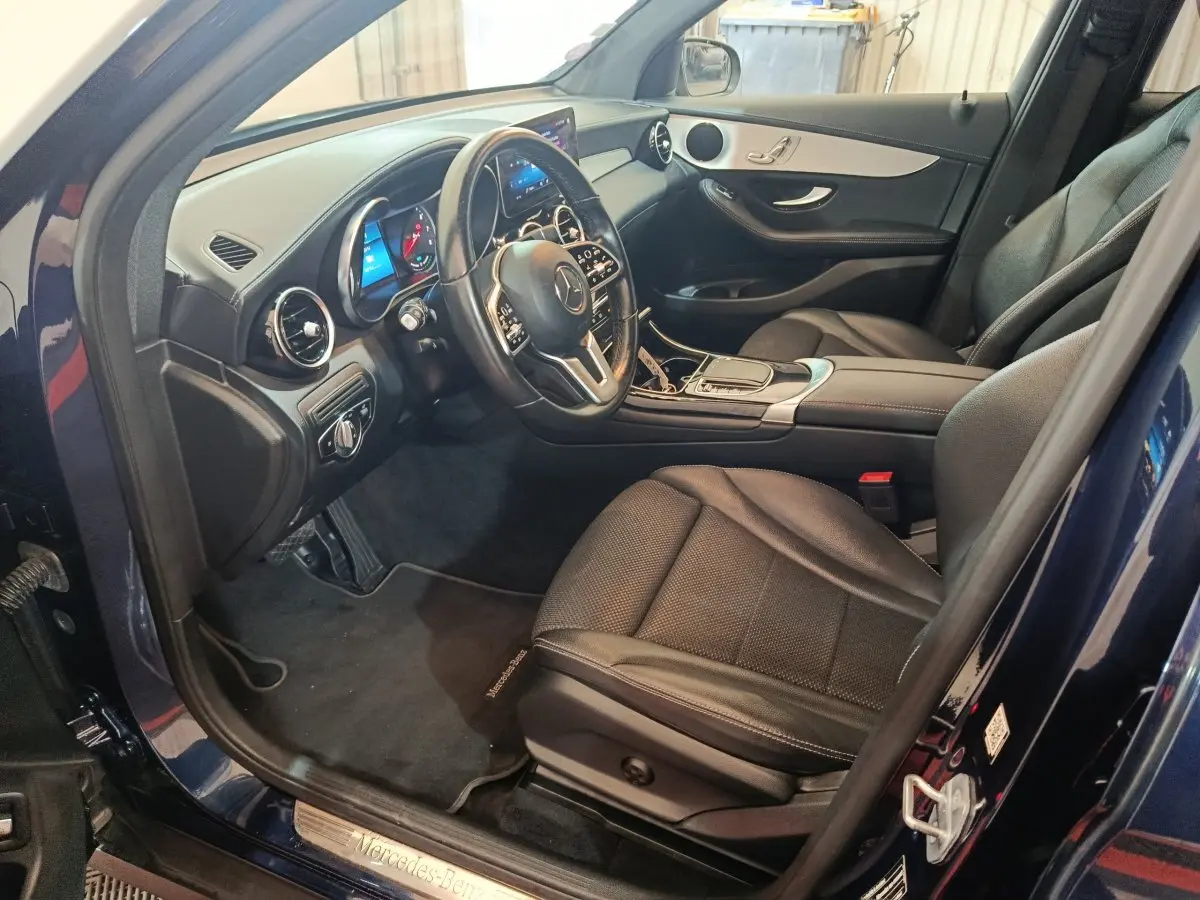 Vue intérieure côté conducteur du Mercedes GLC 300 E Business Line 2021 bleu, avec tableau de bord digital et sièges cuir noirs.