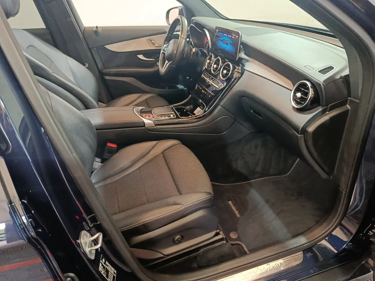 Intérieur avant droit d'un Mercedes GLC bleu 2021, sièges cuir noirs et tableau de bord avec écran tactile.