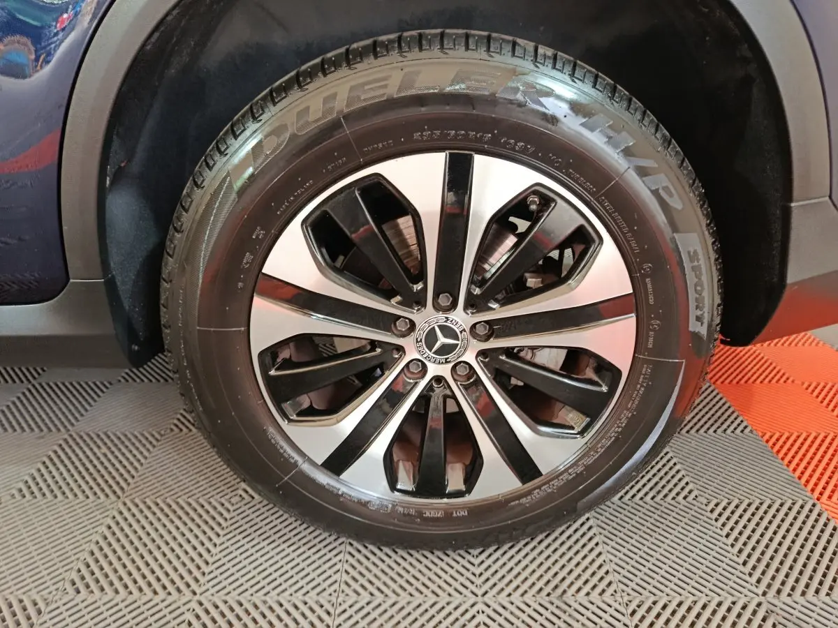 Gros plan sur la roue arrière droite d'un Mercedes GLC 300 E Business Line bleu, montrant le pneu et l'arche de roue.