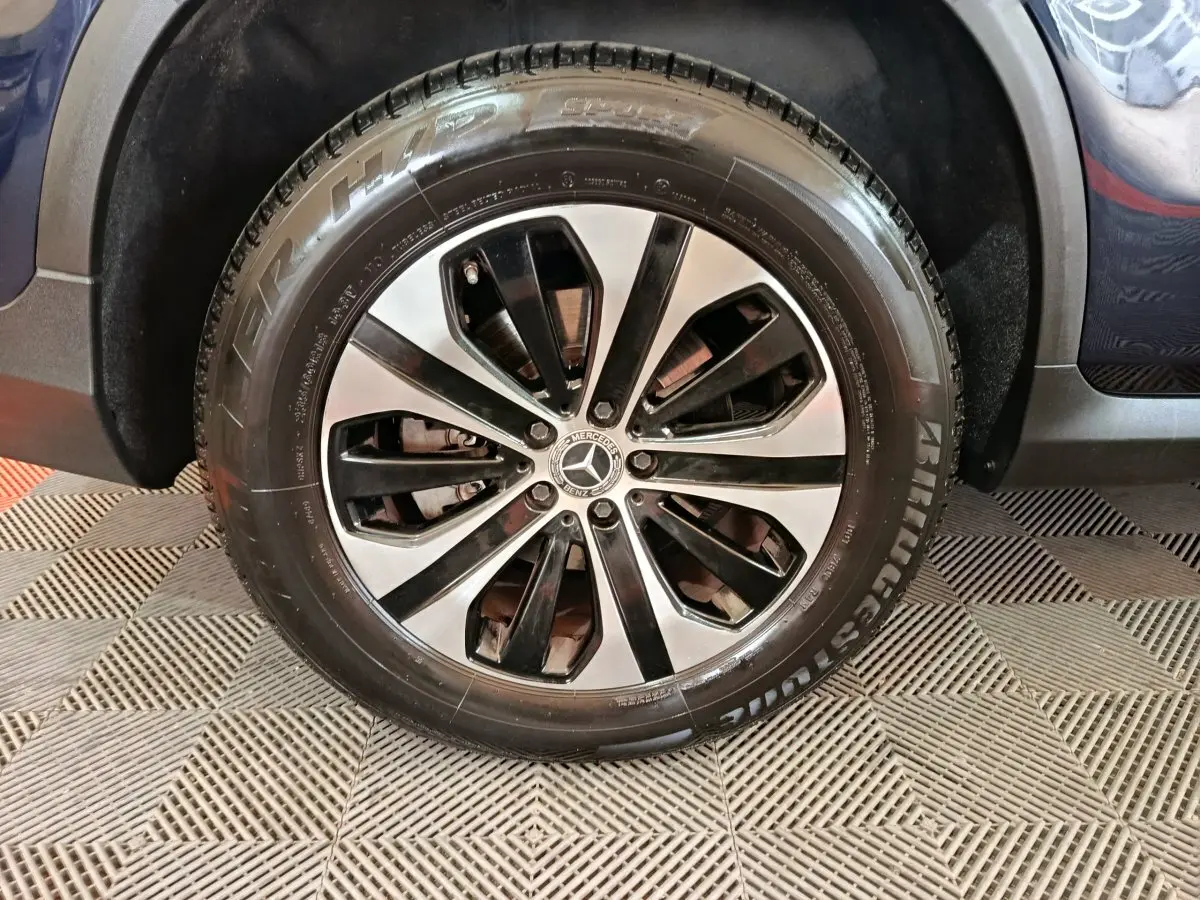 Gros plan sur la roue avant droite du Mercedes GLC 300 E Business Line bleu, jante alliage bicolore et pneu Bridgestone.