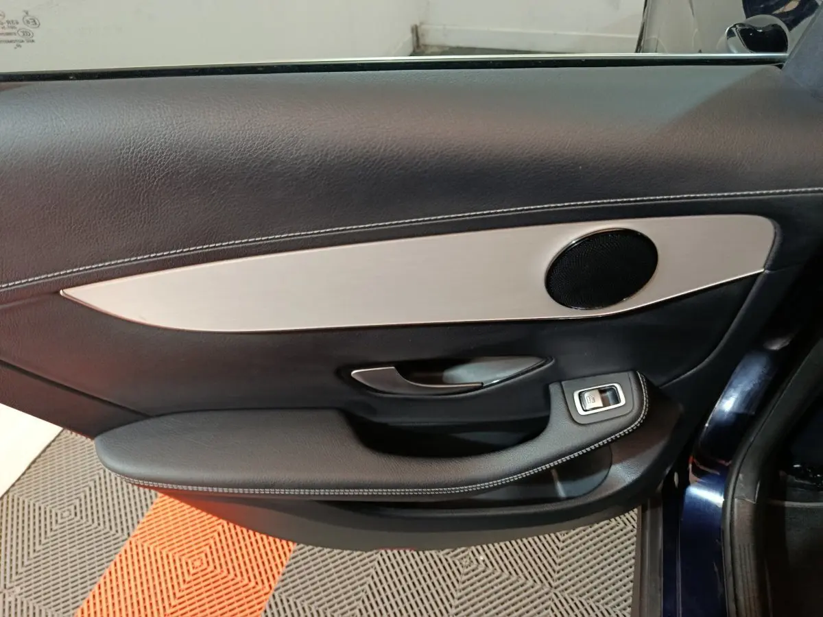 Vue rapprochée de la porte intérieure côté gauche d'un Mercedes GLC 300 E Business Line bleu, avec garniture noire et insert argenté.