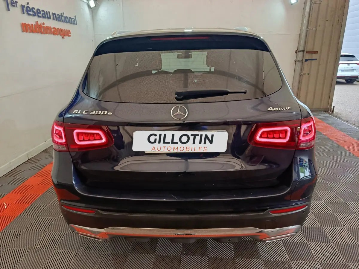 Vue arrière d'un Mercedes GLC 300e bleu avec feux LED allumés et logo 4MATIC visible sur le hayon.