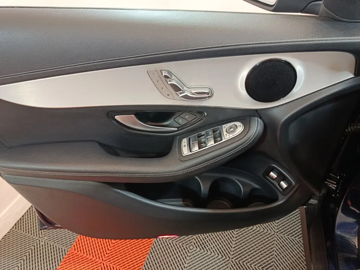 Gros plan sur la porte côté gauche du Mercedes GLC bleu, avec commandes sièges et vitres en aluminium brossé.