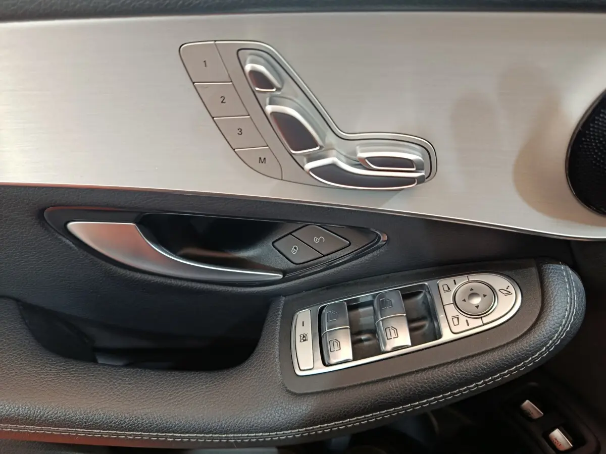 Gros plan sur la porte côté gauche du Mercedes GLC 300 E Business Line 2021, avec commandes sièges et vitres en aluminium brossé.