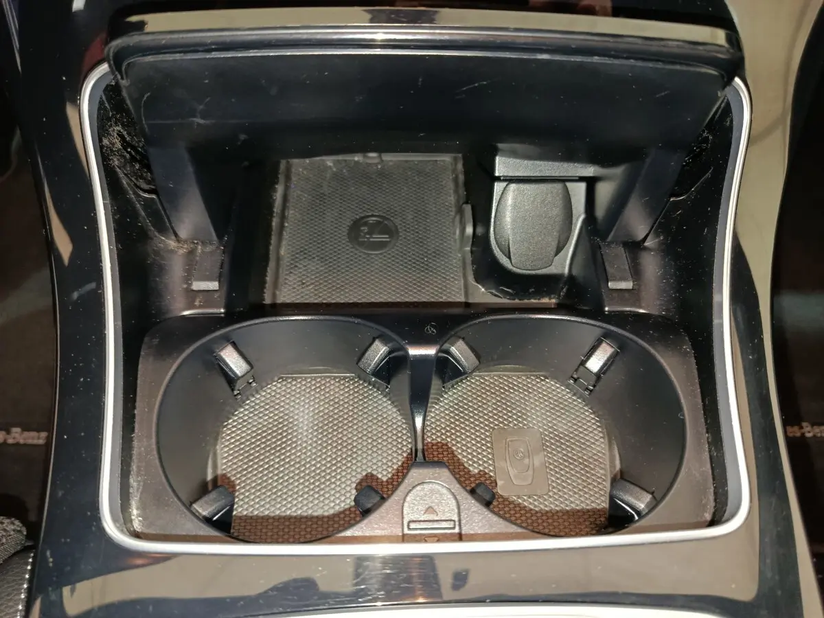 Gros plan sur les porte-gobelets noirs et prise 12V dans la console centrale du Mercedes GLC 300 E bleu 2021.