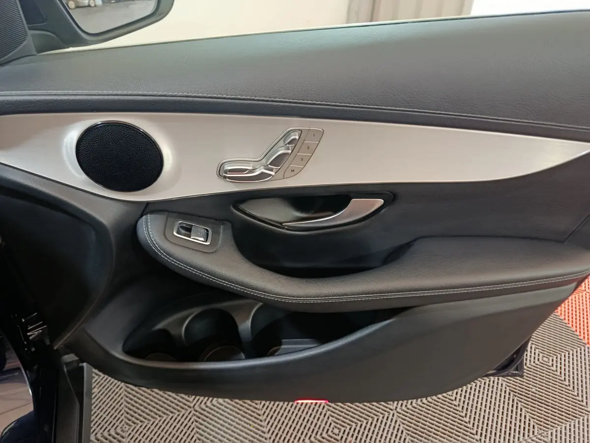 Gros plan sur la porte côté gauche du Mercedes GLC 300 E Business Line bleu, avec commandes sièges et haut-parleur intégré.