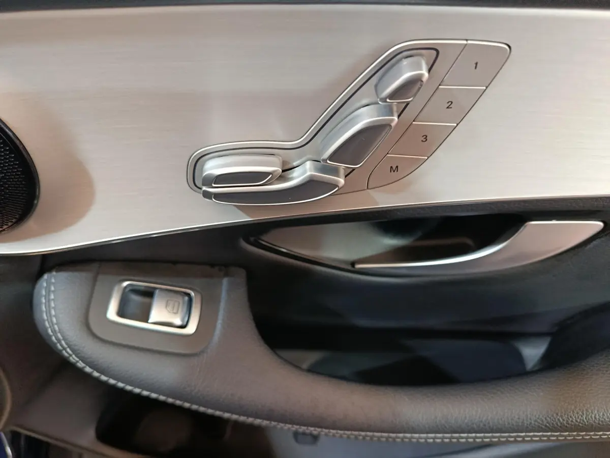 Gros plan sur la commande de réglage des sièges en aluminium brossé côté gauche d'une Mercedes GLC 300 E bleu 2021.