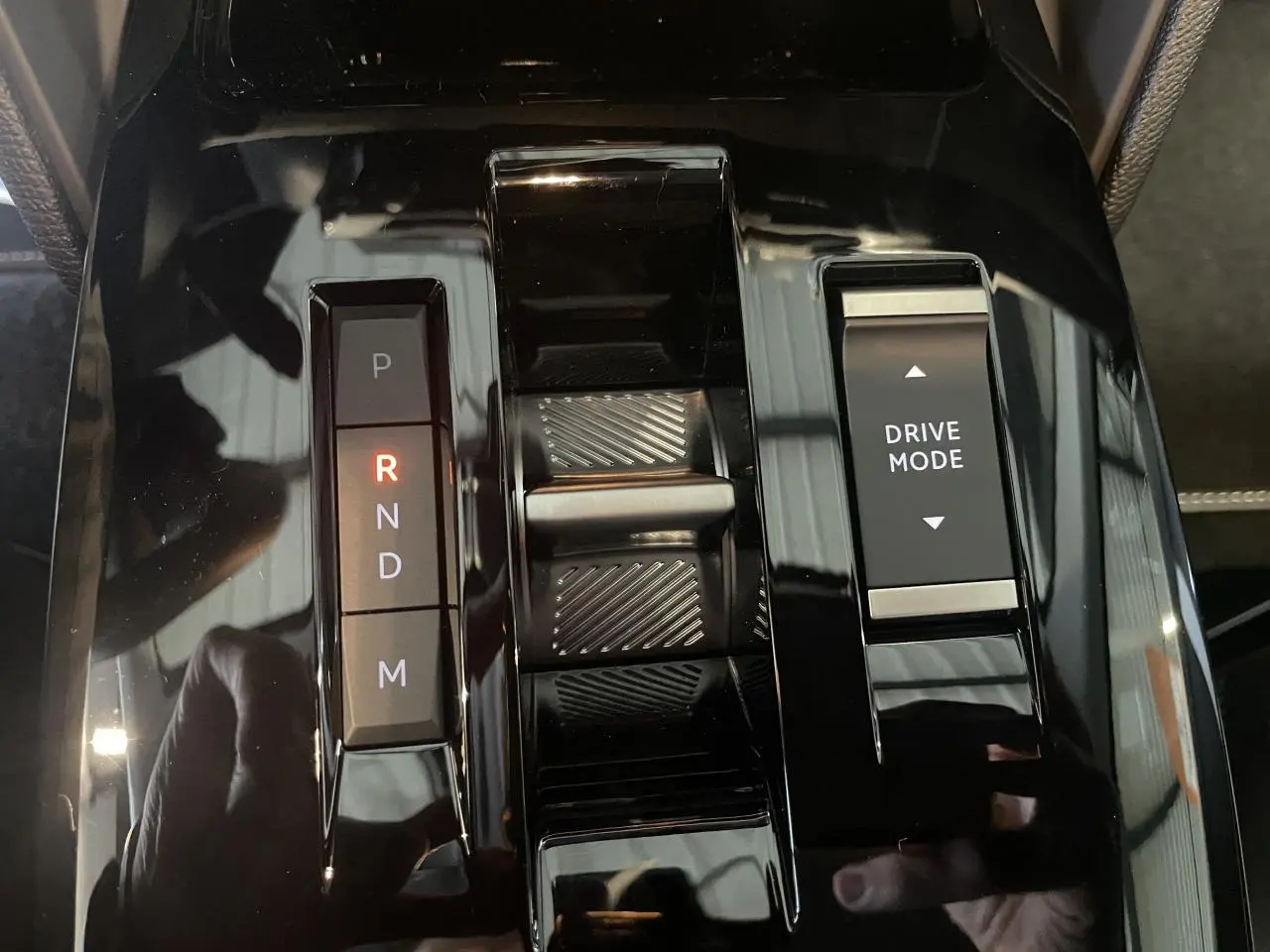 Gros plan sur la console centrale noire brillante de la Citroën C4 hybride avec sélecteur de boîte automatique et bouton Drive Mode.