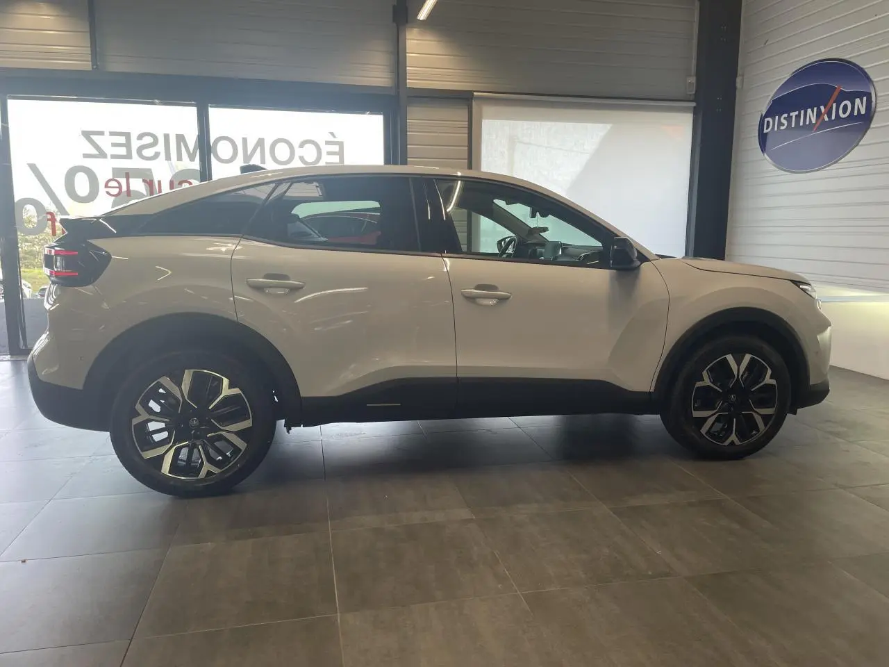 Vue de profil côté gauche d'une Citroën C4 blanche métallisée avec jantes alliage 18 pouces en showroom.