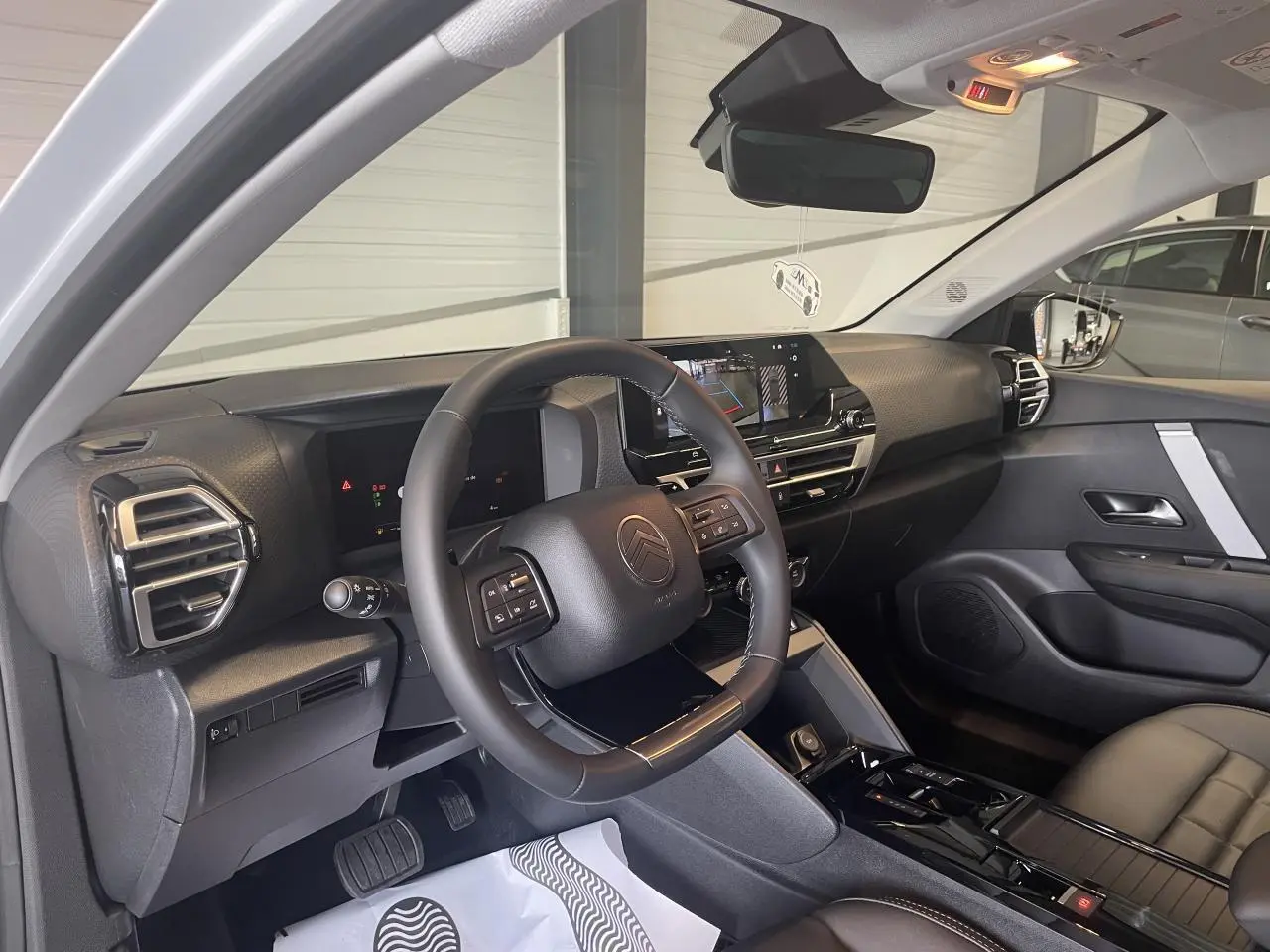 Vue intérieure côté conducteur de la Citroën C4 2025 avec tableau de bord noir et écran tactile central.