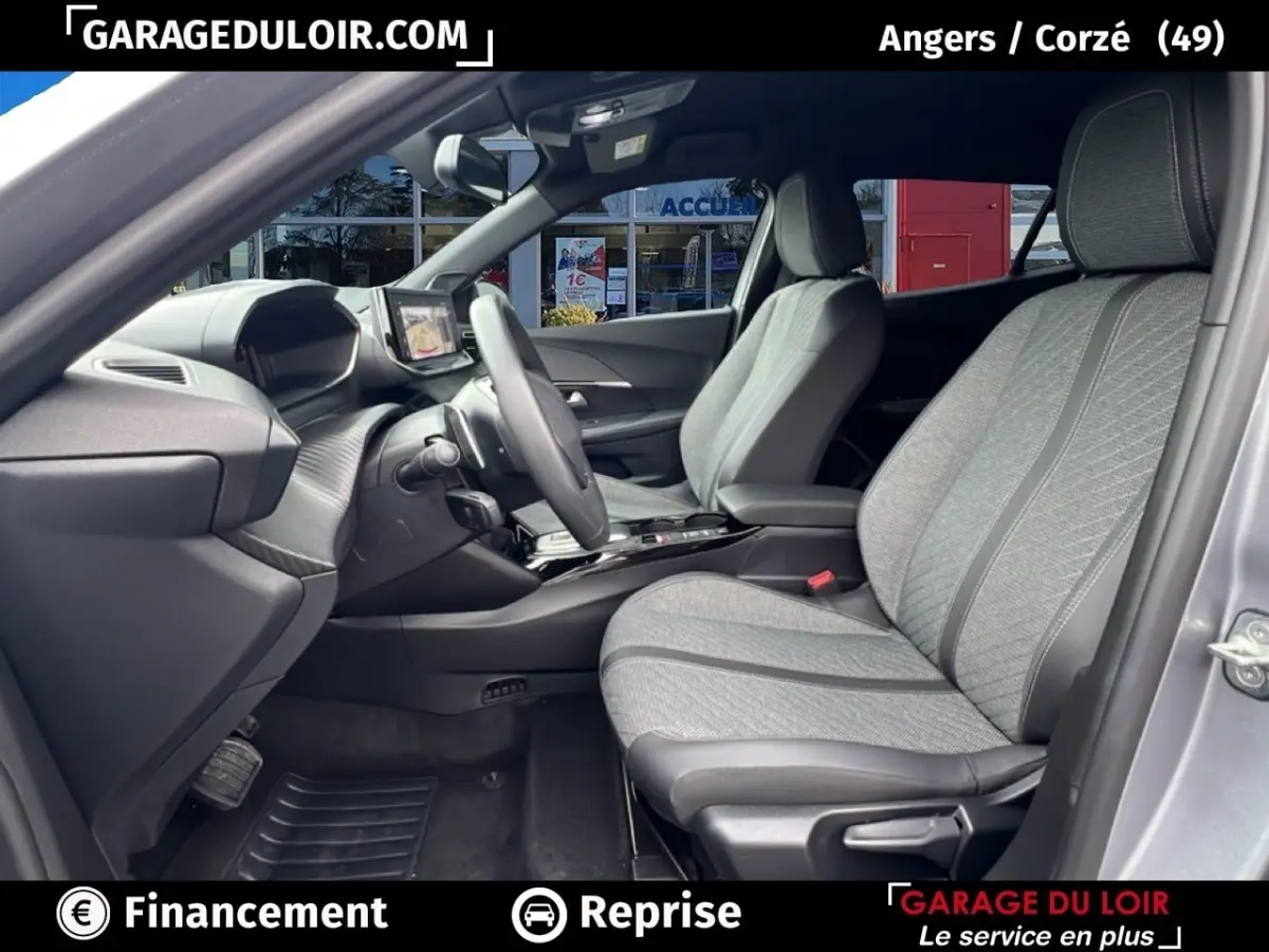 Vue intérieure côté conducteur du Peugeot 2008 Hybrid 136 e-DCS6 Allure 2025 avec sièges tissu gris clair et tableau de bord moderne.