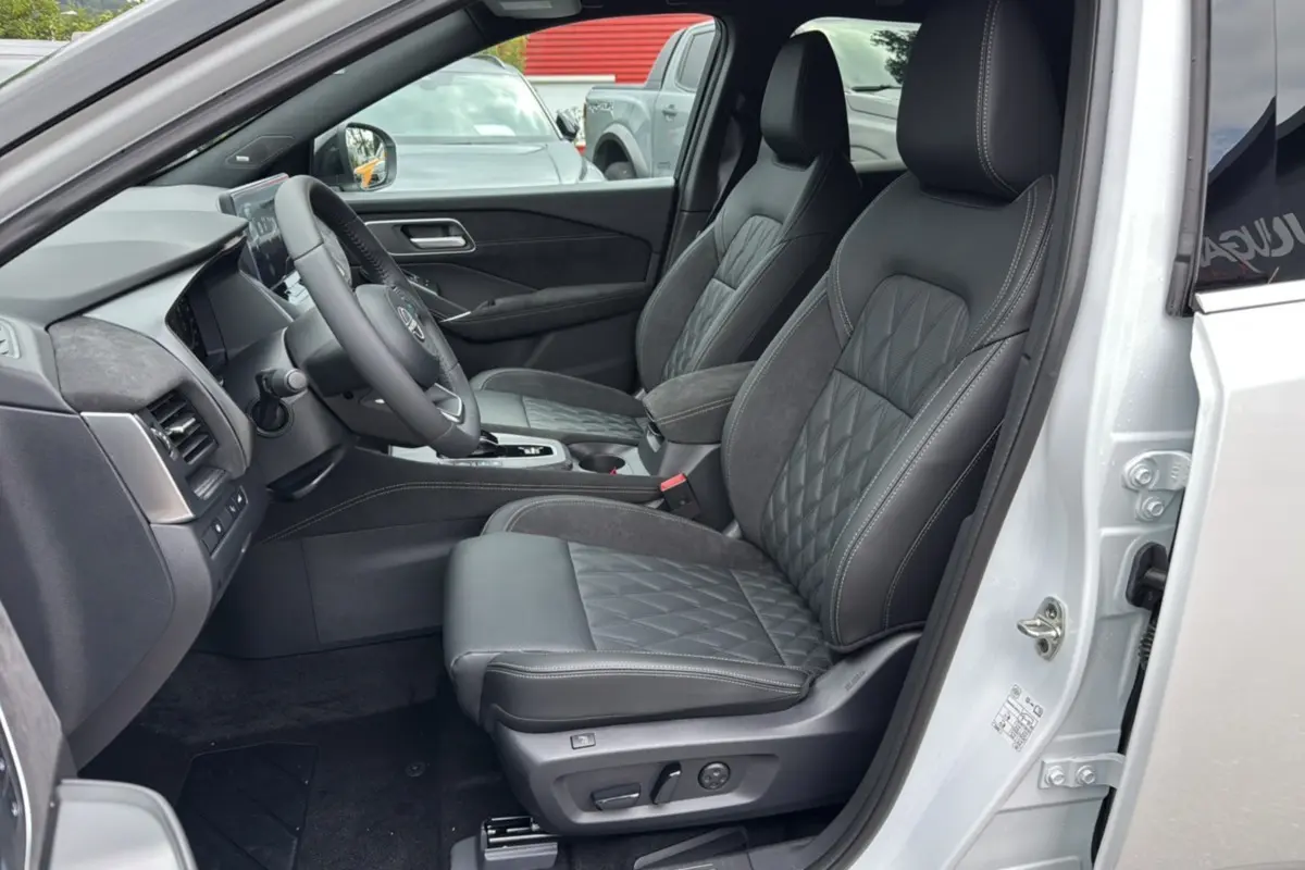 Vue intérieure côté conducteur du Nissan Qashqai E-POWER 205 Tekna Plus blanc lunaire, sièges cuir noirs avec surpiqûres grises.