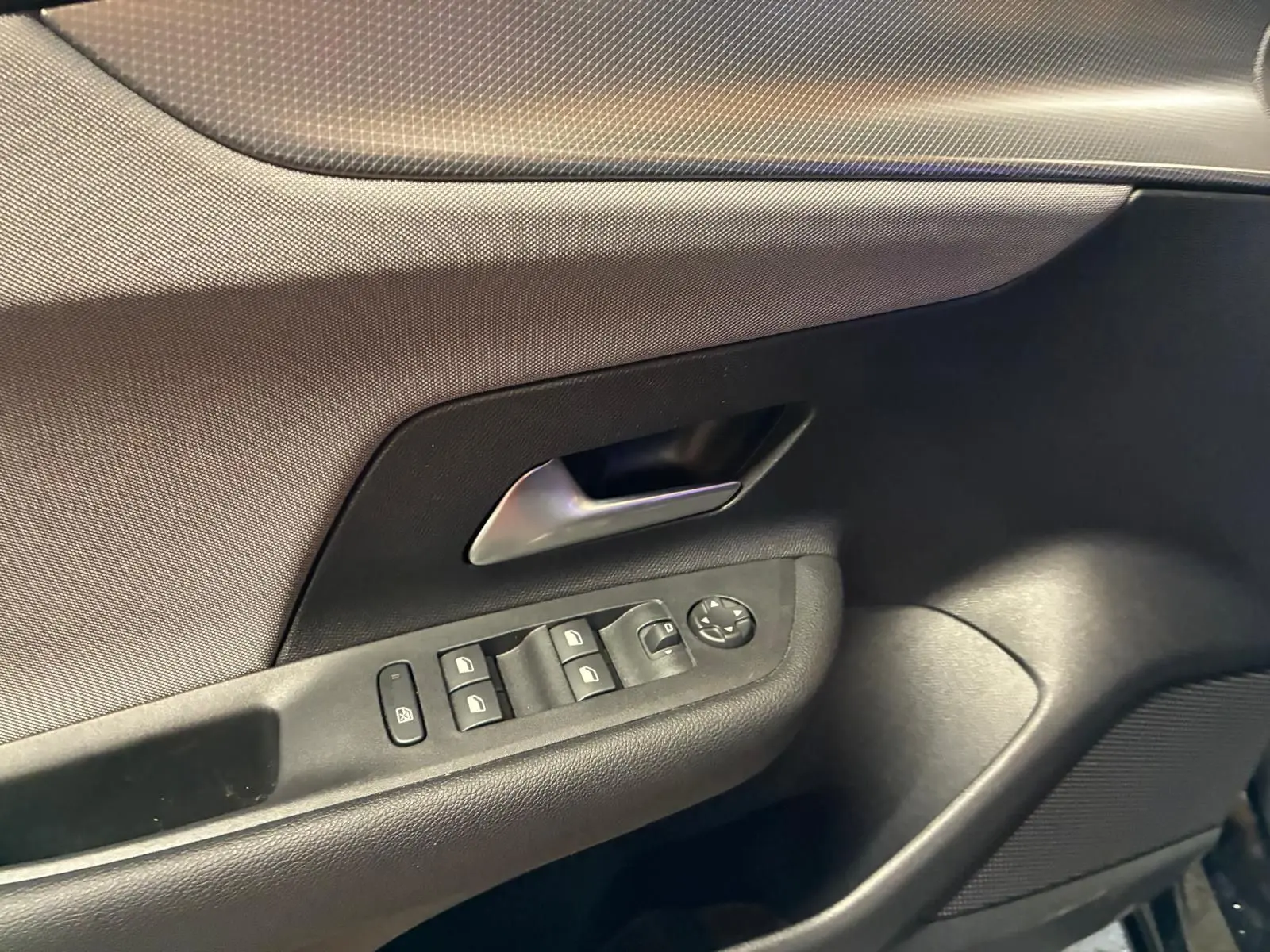 Détail de la porte intérieure côté conducteur de l’Opel Mokka 2025 noire, avec commandes des vitres et poignée argentée.