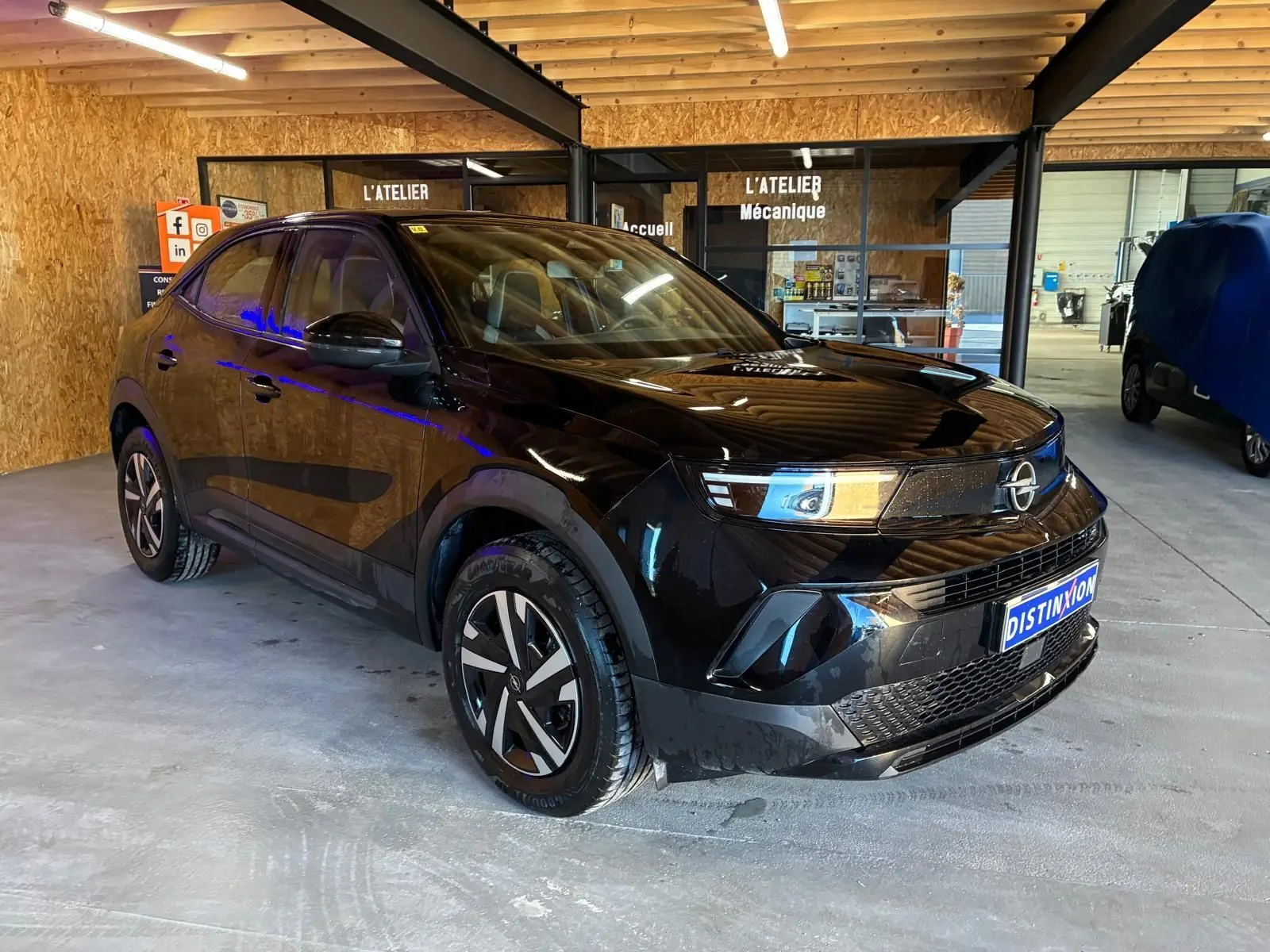Opel Mokka 1.2 Turbo 145 Edition noir en 3/4 avant droit, avec jantes stylisées et calandre moderne dans un atelier.