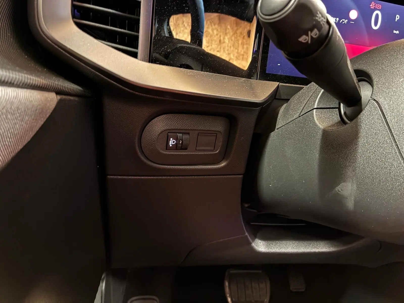 Détail intérieur côté gauche du tableau de bord noir de l’Opel Mokka 2025 avec commande de réglage des phares.