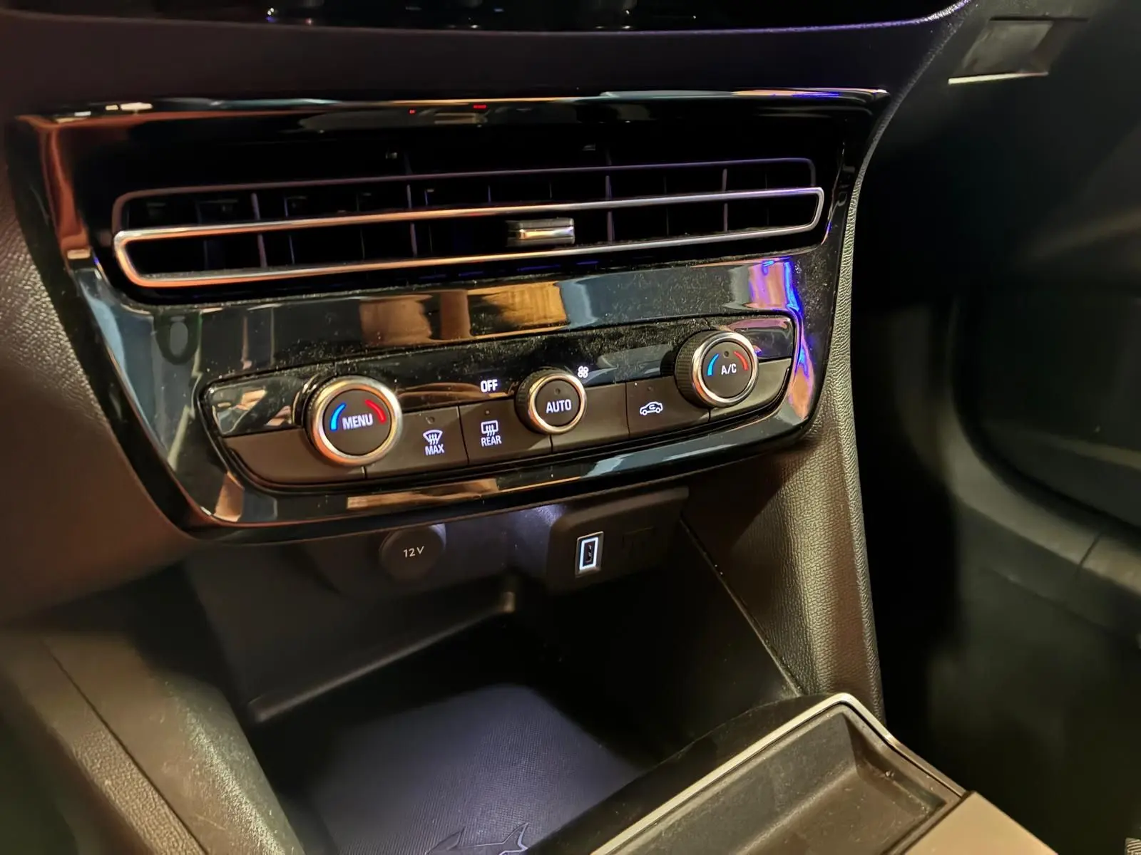 Vue rapprochée de la console centrale noire de l’Opel Mokka 1.2 Turbo 145 Edition avec commandes de climatisation et prises USB.