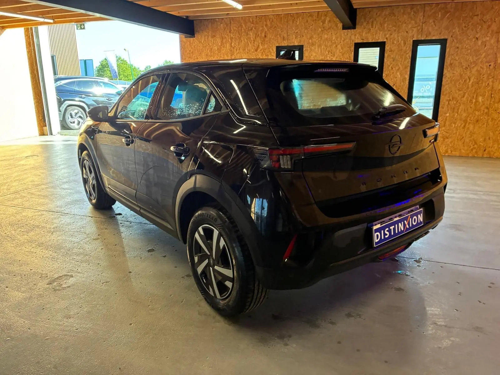 Opel Mokka noir 2025 vue 3/4 arrière droit en intérieur, avec jantes alliage et feux LED distinctifs.