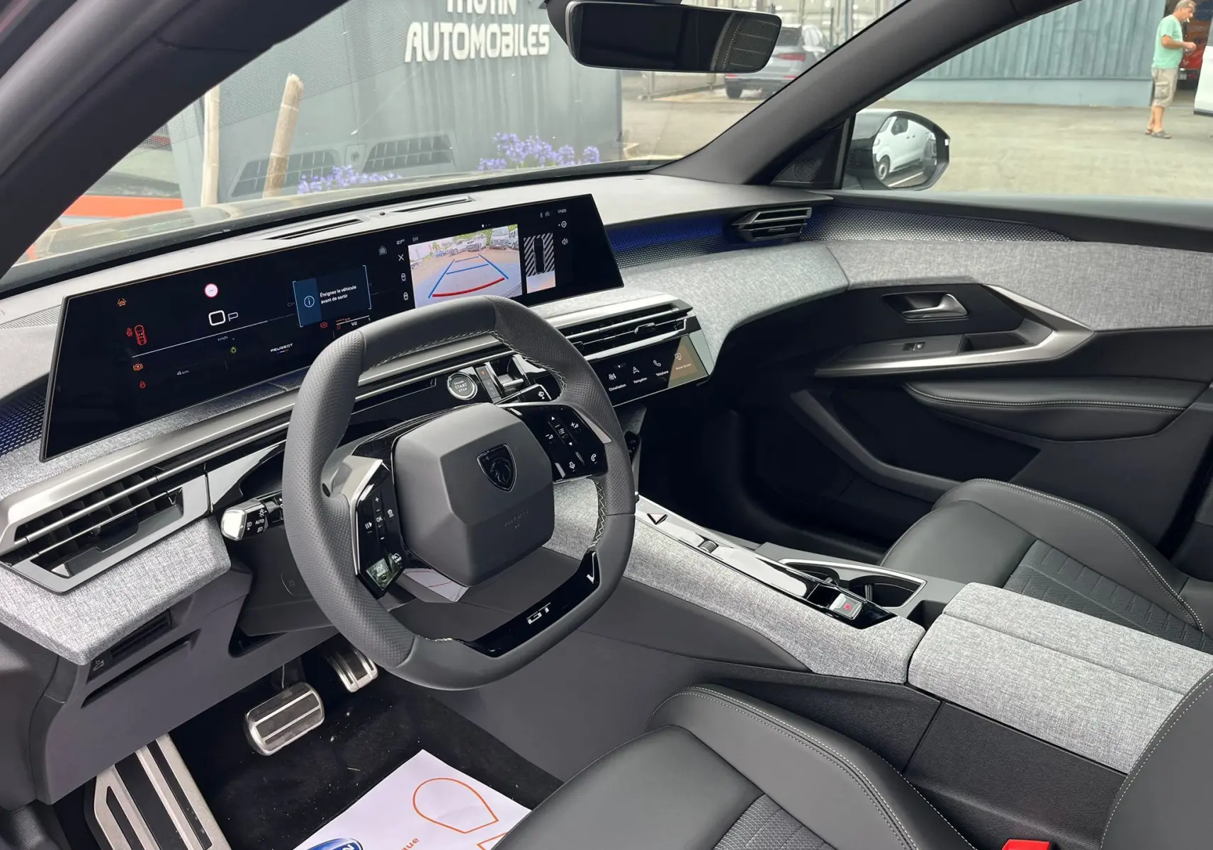 Intérieur du Peugeot 3008 Nouveau 2025, vue côté conducteur, tableau de bord gris clair et sièges noirs cuir.