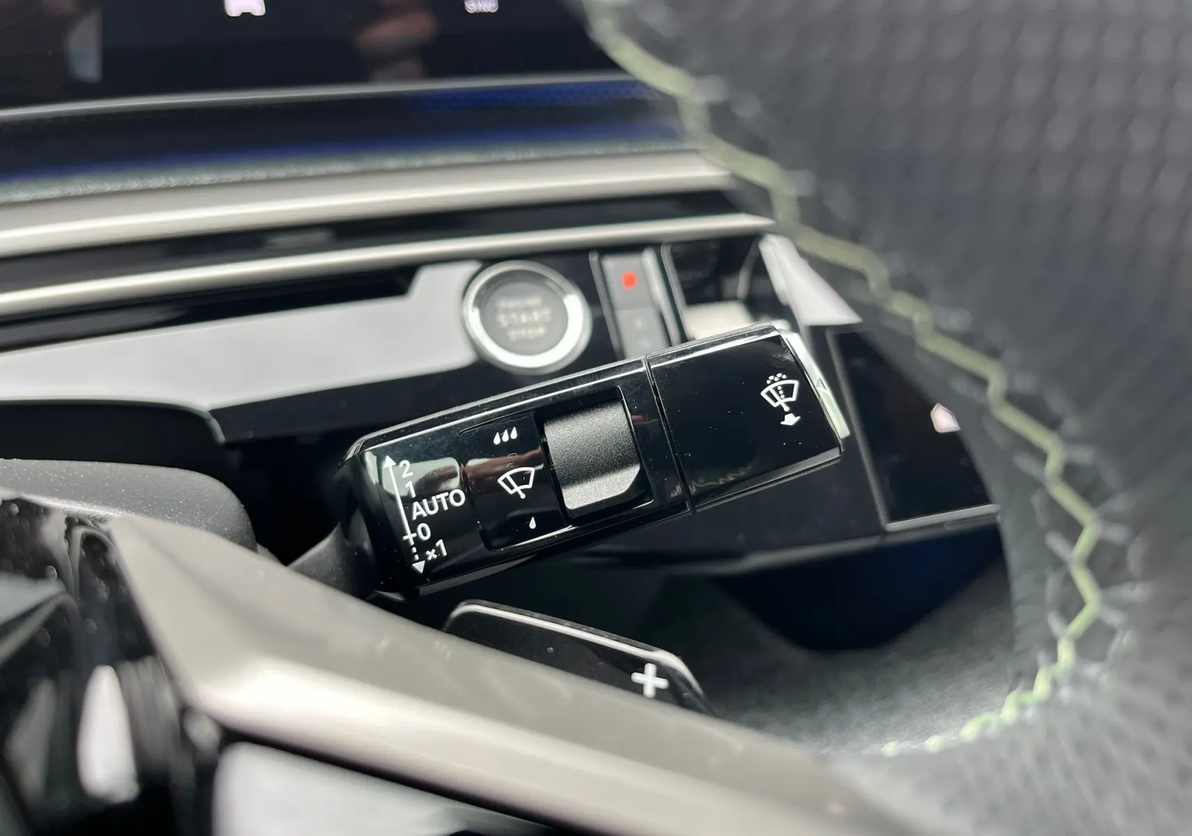 Gros plan sur la commande d'essuie-glace du Peugeot 3008 gris titane, avec volant partiellement visible en cuir noir.
