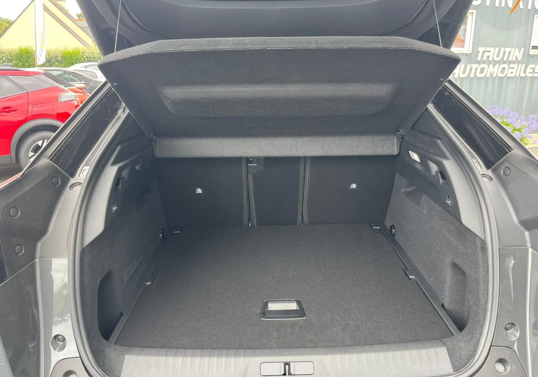 Coffre ouvert vu de l'arrière d'un Peugeot 3008 gris titane, intérieur spacieux et habillage noir.