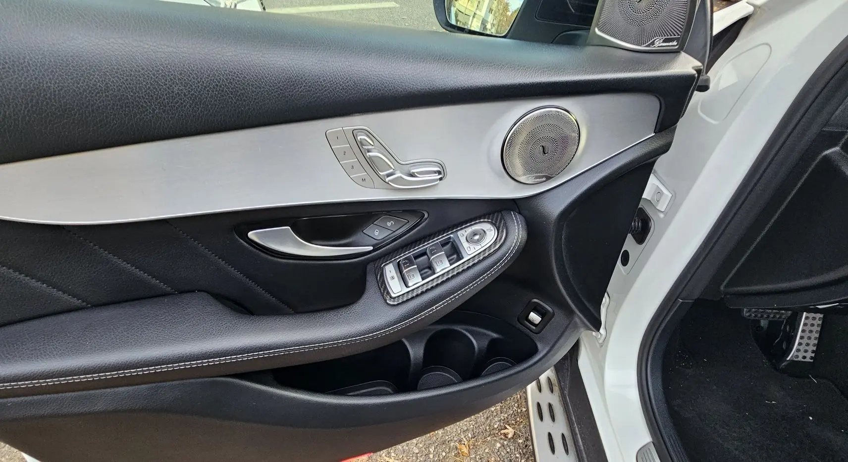 Détail de la porte avant gauche d'un Mercedes GLC Coupé blanc, avec commandes de vitres et haut-parleur argenté.