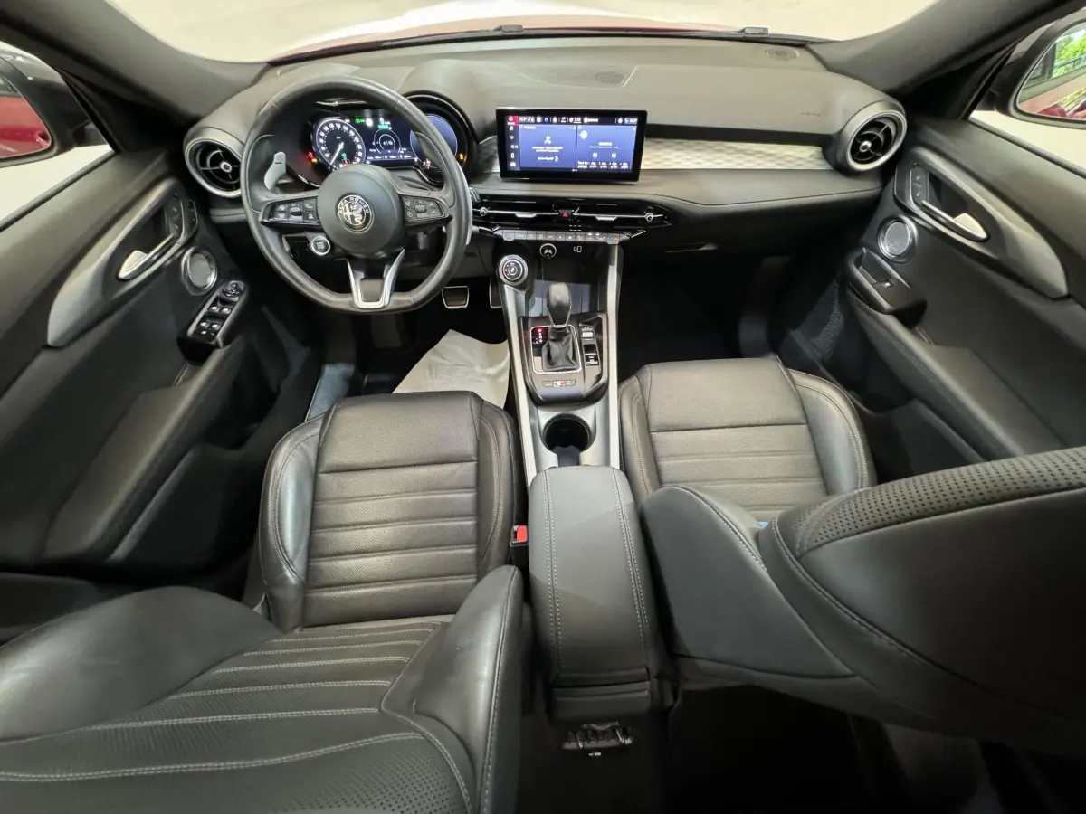Intérieur noir cuir de l'Alfa Romeo Tonale 2023, vue de face sur tableau de bord et console centrale moderne.