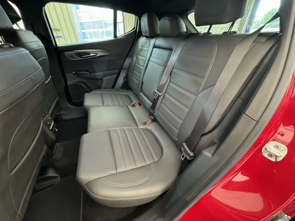 Vue côté droit des sièges arrière en cuir noir de l'Alfa Romeo Tonale rouge, avec ceinture de sécurité et portière ouverte.