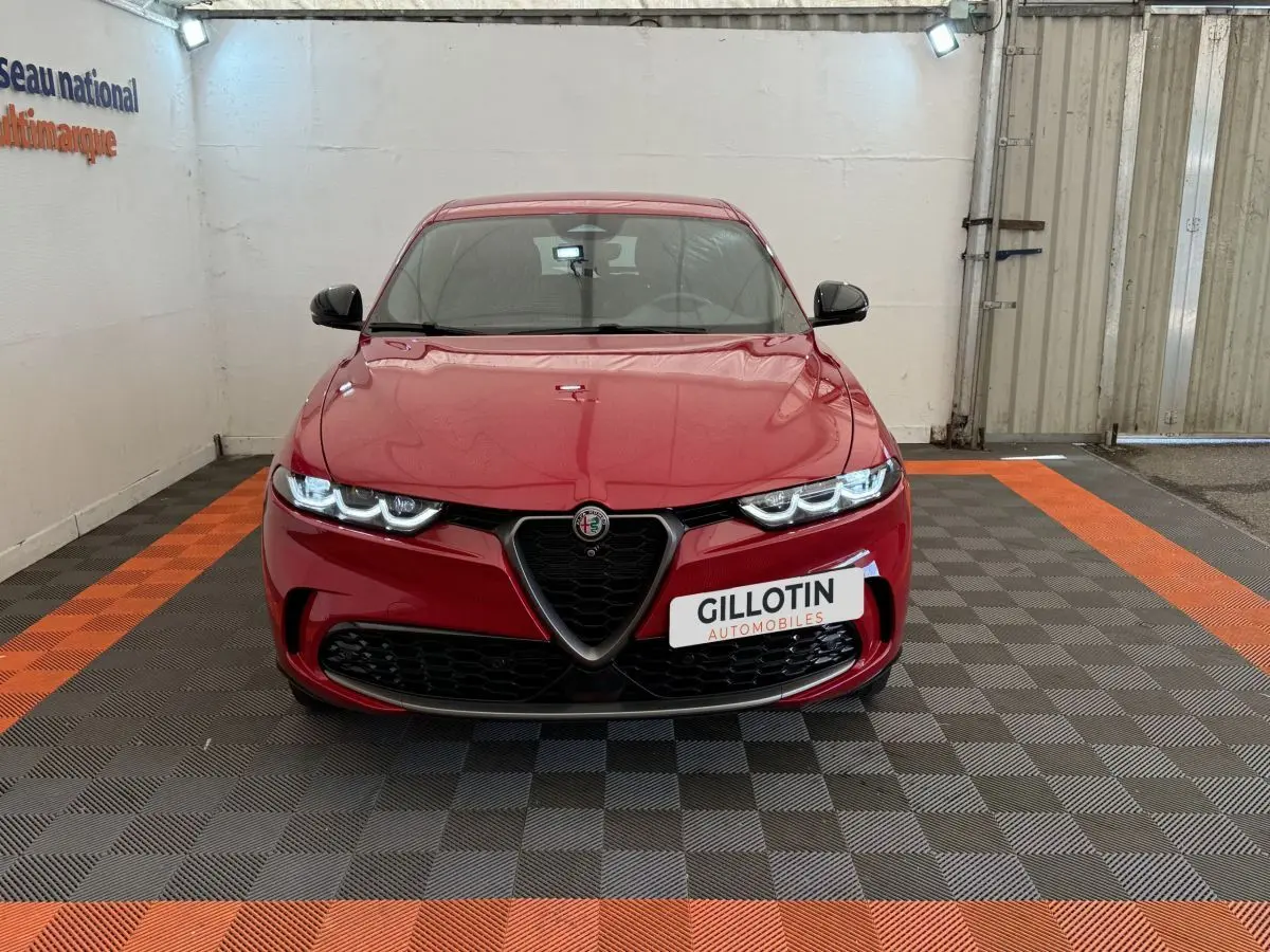 Vue frontale d'une Alfa Romeo Tonale rouge avec calandre caractéristique en V et phares LED allumés.