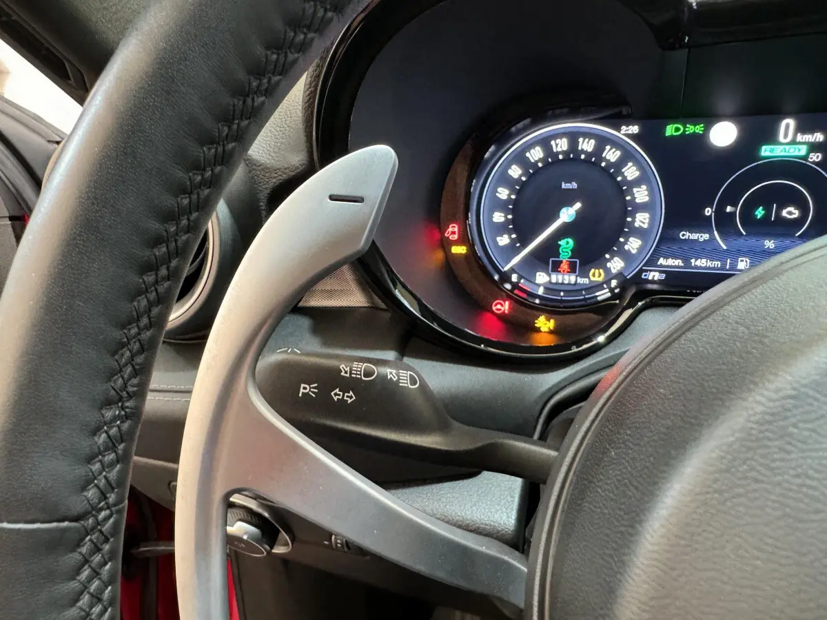 Vue rapprochée du tableau de bord et volant de l'Alfa Romeo Tonale rouge, affichage digital et commandes au volant visibles.