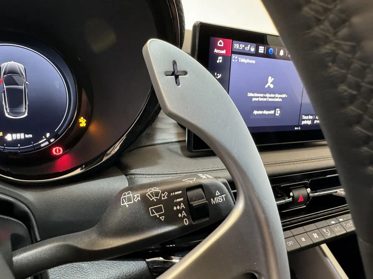 Gros plan intérieur sur la palette de changement de vitesse côté droit et l'écran tactile du tableau de bord de l'Alfa Romeo Tonale rouge.