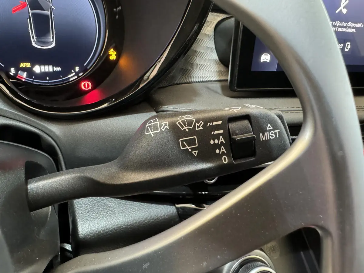 Gros plan sur la commande d’essuie-glace à gauche du volant dans l’habitacle de l’Alfa Romeo Tonale rouge 2023.