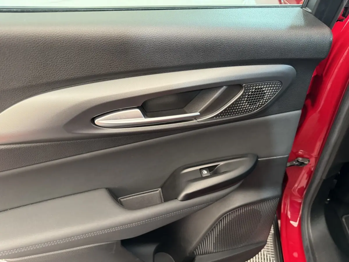 Gros plan sur la porte côté conducteur noire avec poignée alu et cadre rouge vif visible sur une Alfa Romeo Tonale 2023.