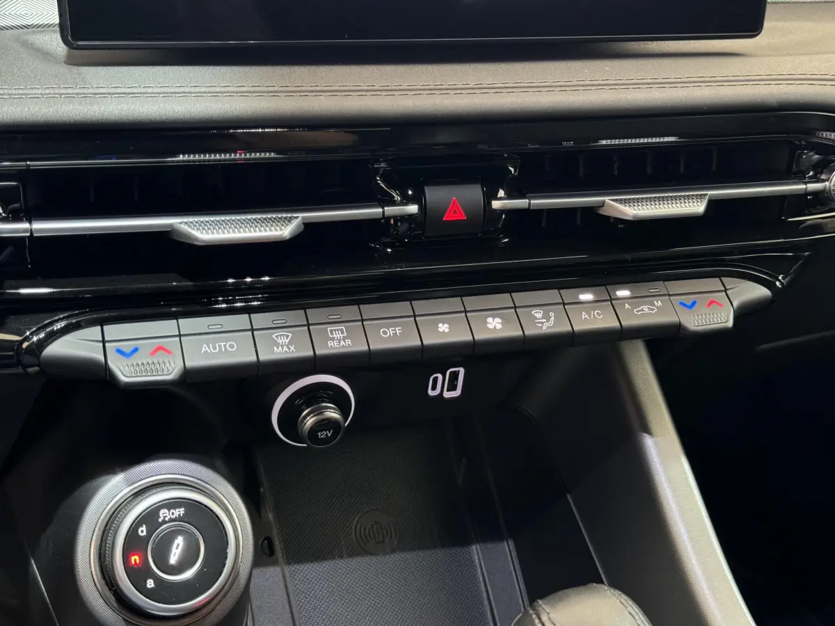 Vue rapprochée du tableau de bord noir de l'Alfa Romeo Tonale rouge, montrant les commandes climatisation et la molette de sélection.