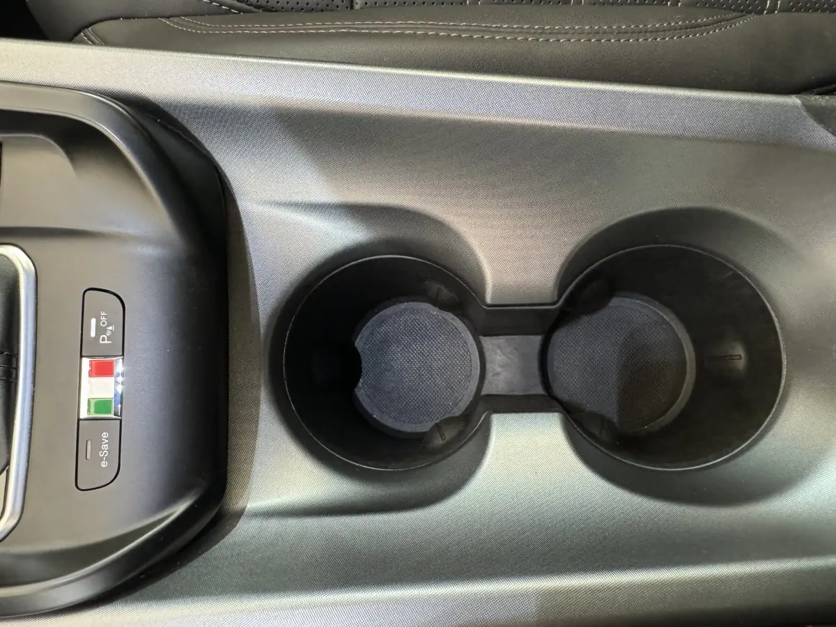Gros plan sur la console centrale noire avec porte-gobelets et boutons e-Save et parking de l'Alfa Romeo Tonale rouge 2023.