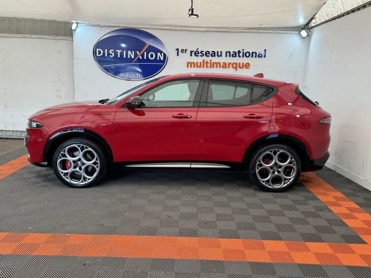 Profil côté gauche d'un Alfa Romeo Tonale rouge 2023 avec jantes distinctives en cercle et logo Distinxion en arrière-plan.