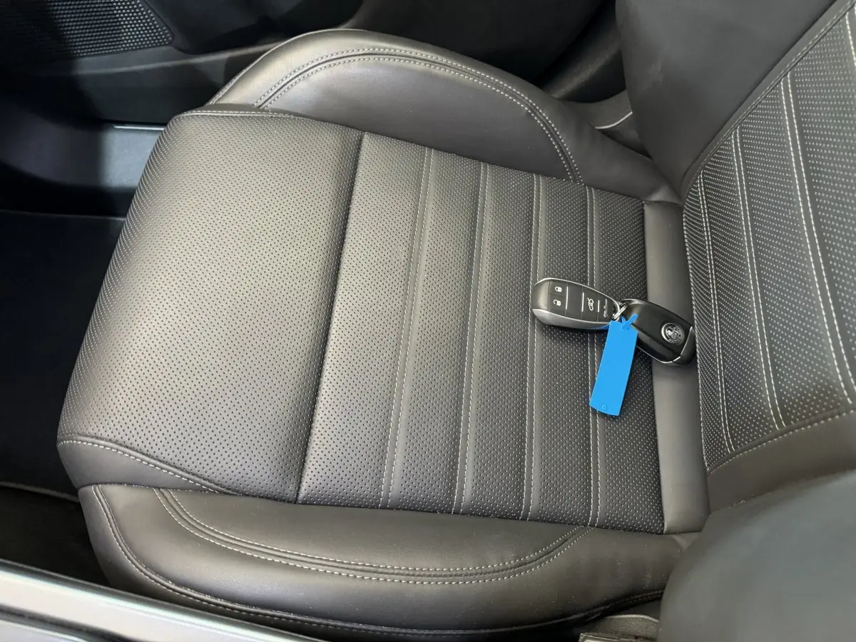 Gros plan sur le siège conducteur en cuir noir perforé avec clé et badge Alfa Romeo posés dessus.