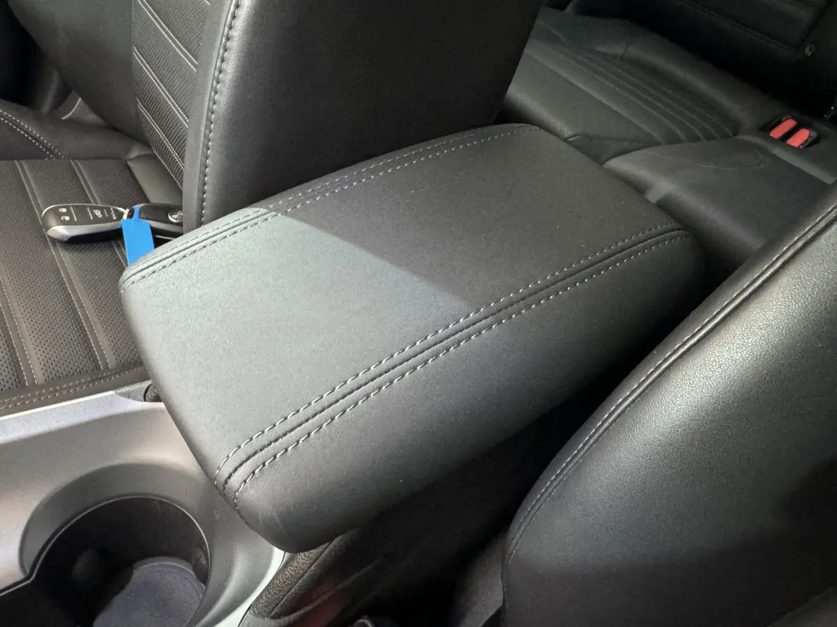 Accoudoir central en cuir noir avec coutures apparentes dans l'habitacle d'une Alfa Romeo Tonale rouge 2023.