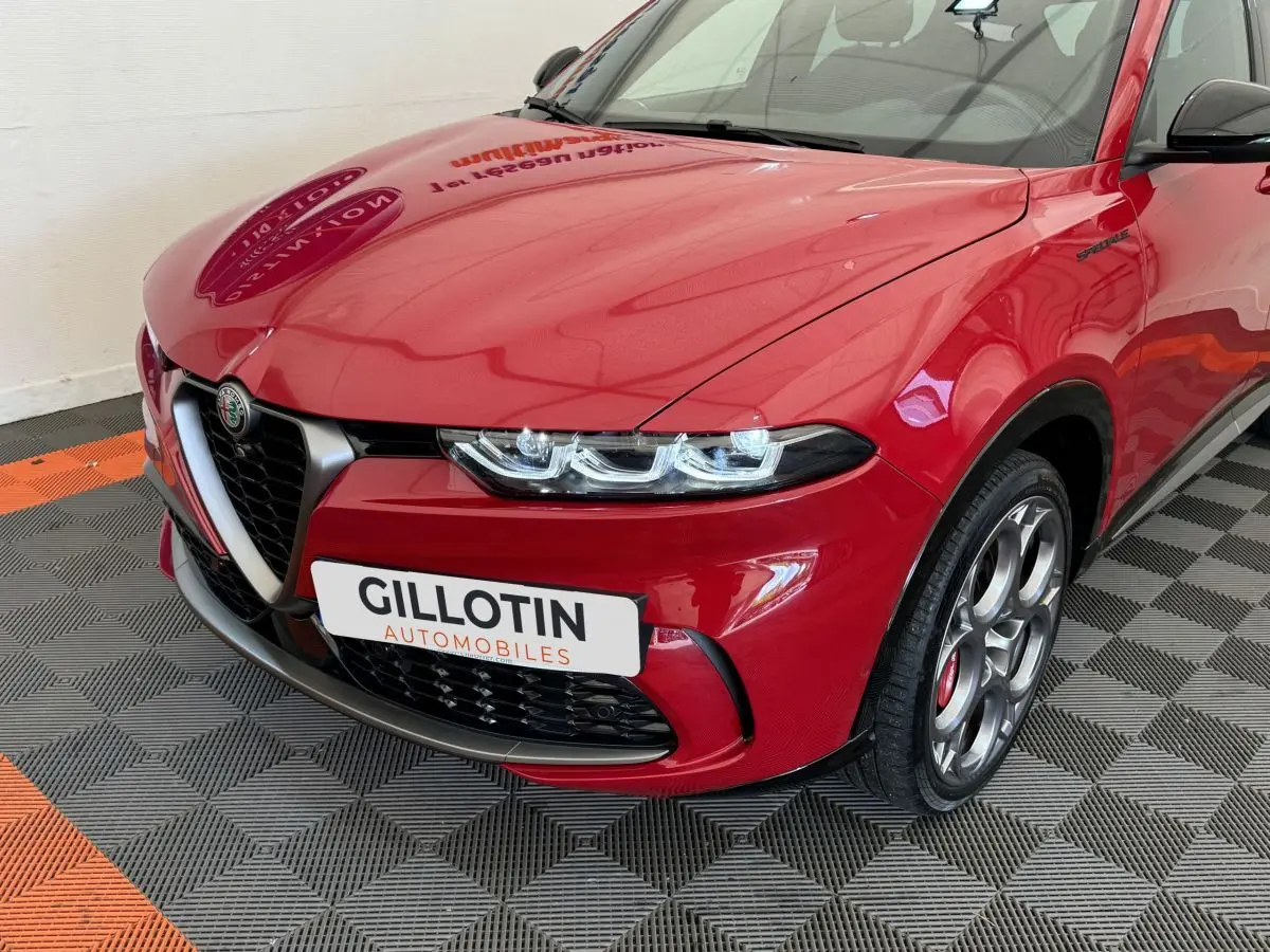 Vue 3/4 avant gauche d'une Alfa Romeo Tonale rouge avec calandre caractéristique et jantes spécifiques Edizione Speciale.