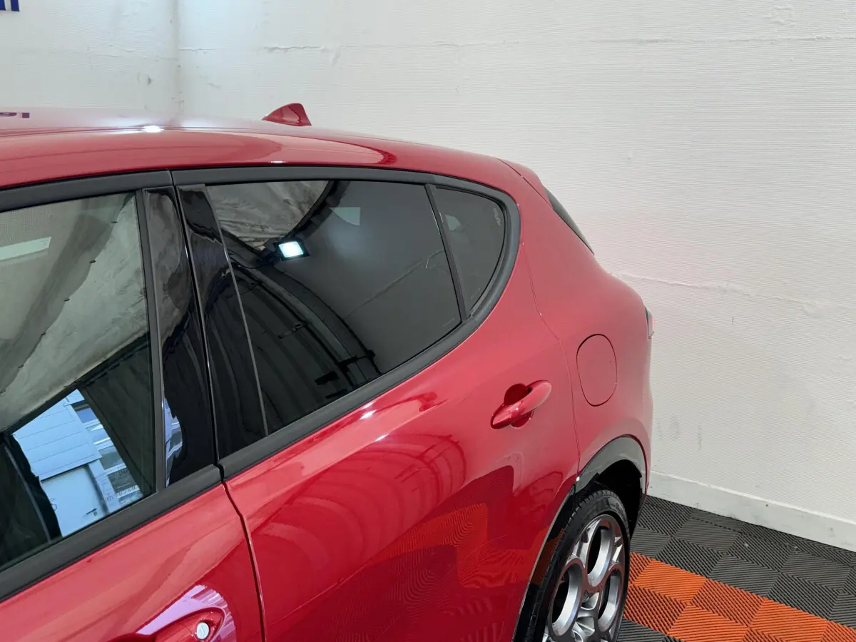 Vue côté arrière gauche de l'Alfa Romeo Tonale rouge 2023 avec jantes distinctives et vitres teintées.