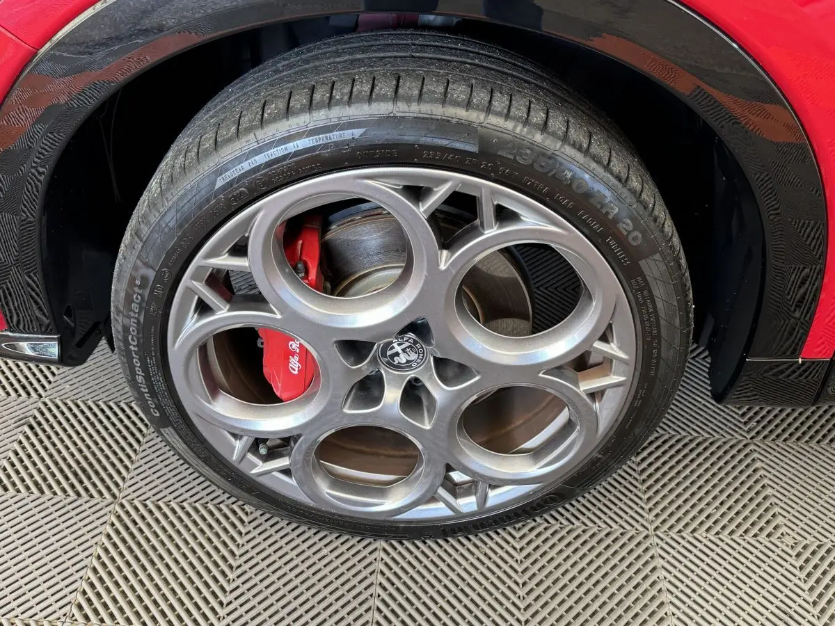 Gros plan sur la roue avant droite rouge d'une Alfa Romeo Tonale 2023 avec étrier de frein rouge et jante alu distinctive.