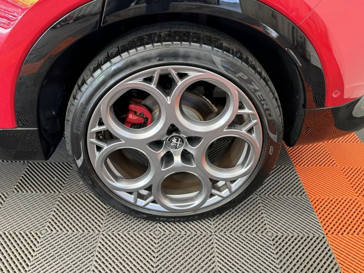 Gros plan sur la roue arrière droite de l'Alfa Romeo Tonale rouge, avec jante alliage et pneu Pirelli P Zero.