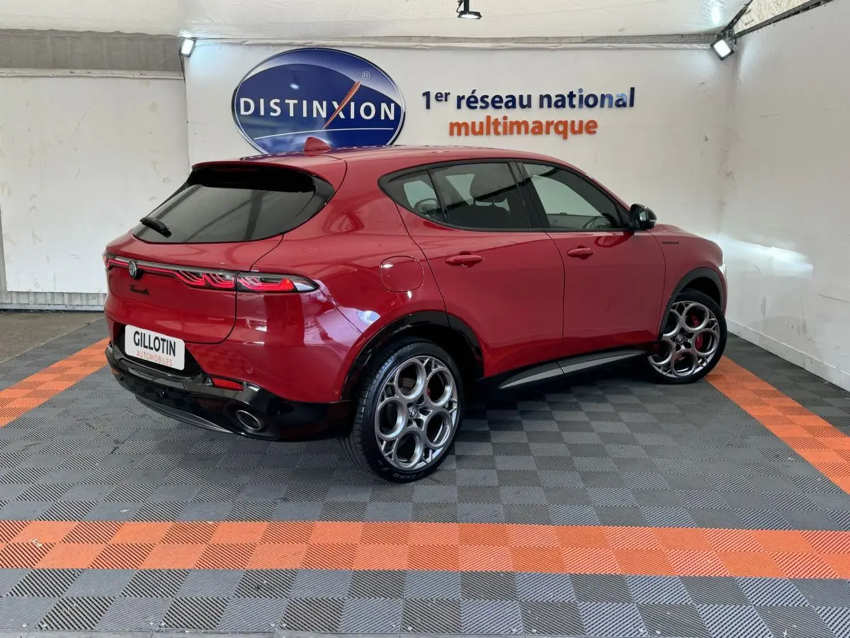 Vue 3/4 arrière droite d'une Alfa Romeo Tonale rouge 2023 avec jantes distinctives et feux arrière LED allongés.