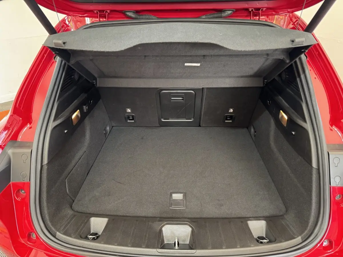 Coffre ouvert vu de l'arrière d'une Alfa Romeo Tonale rouge, montrant un espace de chargement propre et bien éclairé.