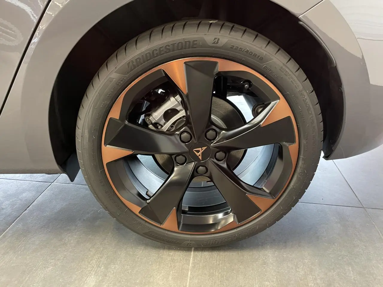 Gros plan sur la jante alliage 18'' cuivrée et noire de la CUPRA Leon gris, avec logo Cupra central visible.