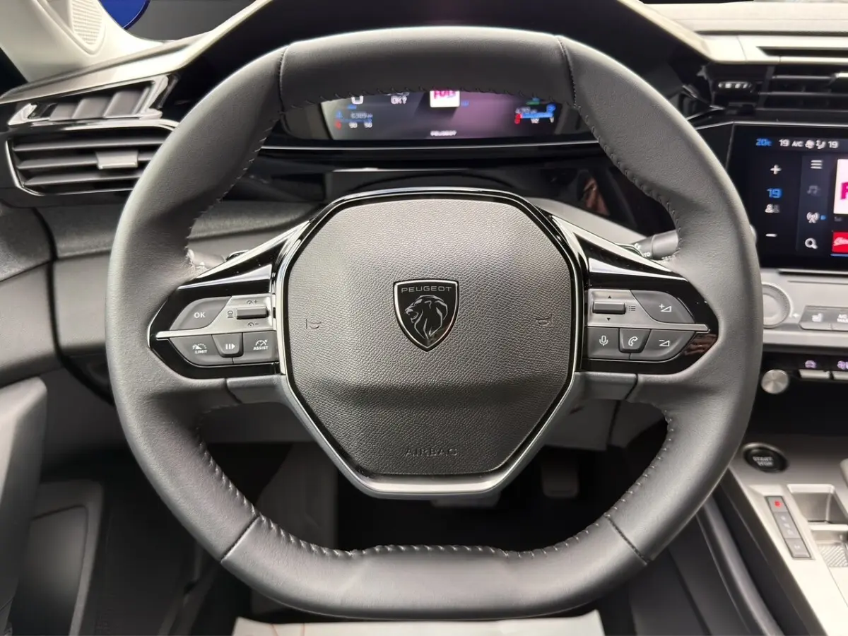 Vue rapprochée du volant cuir noir de la Peugeot 308 Hybrid 145 e-DCS6 Allure avec commandes multifonctions intégrées.