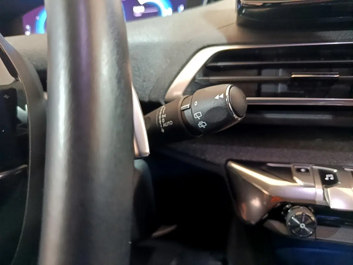 Détail intérieur du Peugeot 3008 bleu 2021 montrant le commodo d'essuie-glace et partie du tableau de bord côté conducteur.