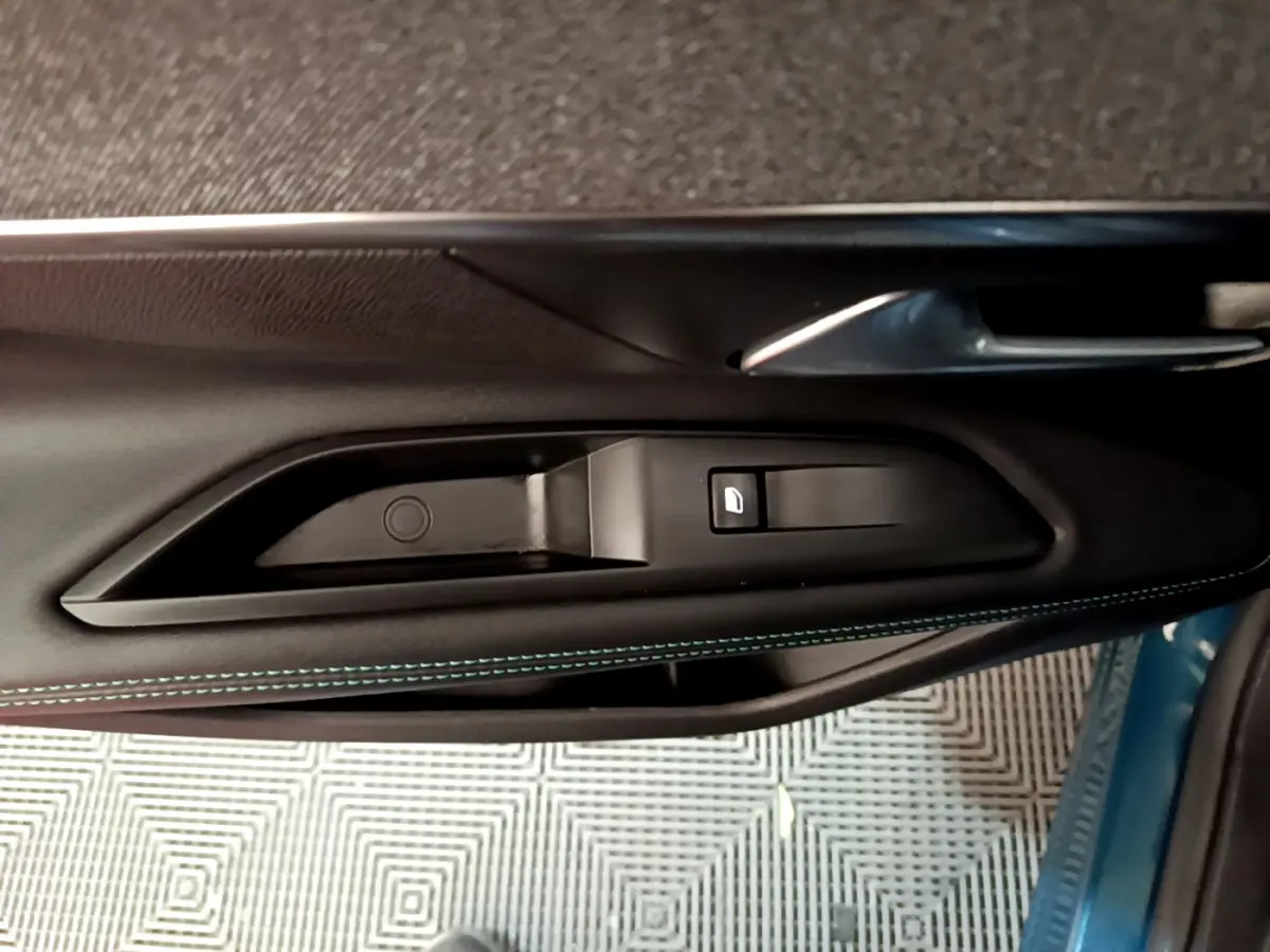 Poignée intérieure et commande de lève-vitre côté gauche en cuir noir avec surpiqûres bleues du Peugeot 3008 bleu hybride rechargeable.