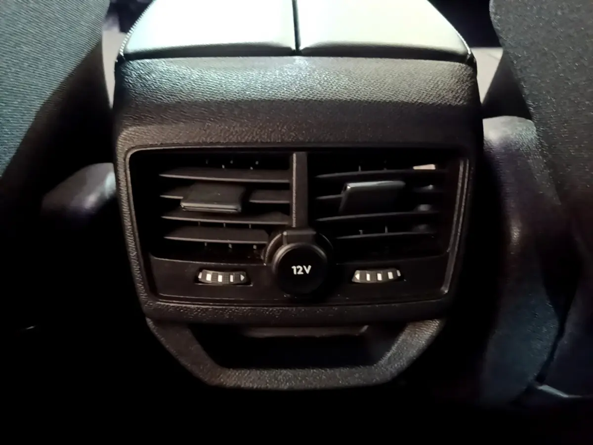 Gros plan sur la sortie d'air arrière noire avec prise 12V du Peugeot 3008 hybride rechargeable bleu 2021.