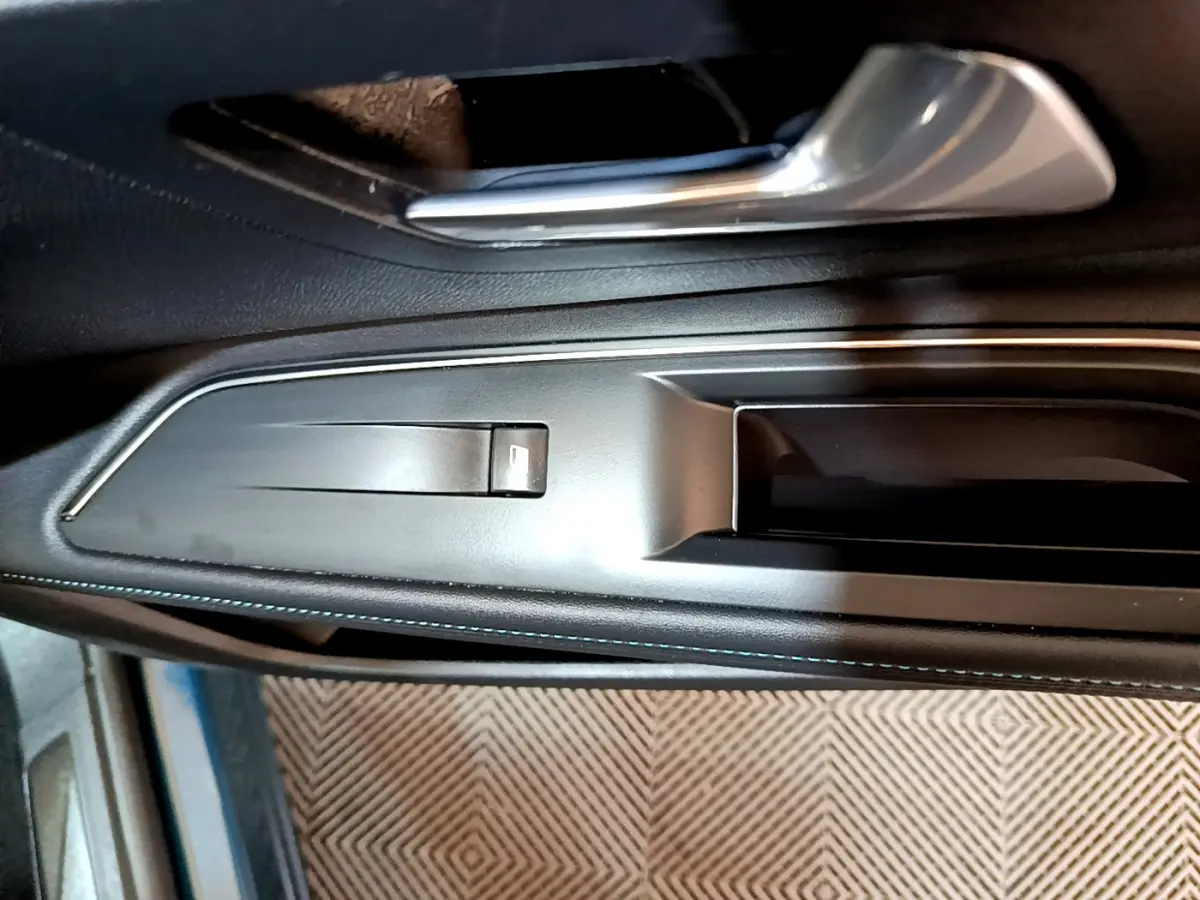 Poignée intérieure côté gauche en plastique noir et métal brossé du Peugeot 3008 hybride rechargeable bleu 2021.